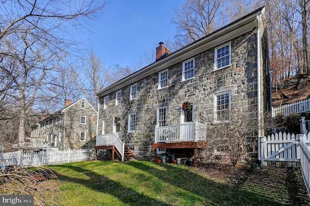 rear view of house featuring a wooden deck and a yard