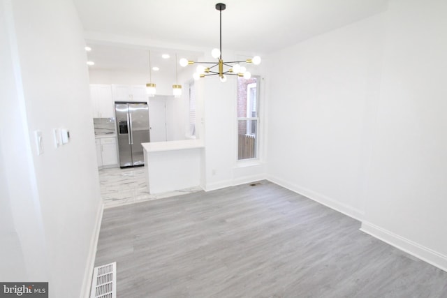 unfurnished dining area with a chandelier and light wood-type flooring