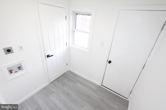 laundry area featuring electric dryer hookup, hookup for a washing machine, and light hardwood / wood-style flooring