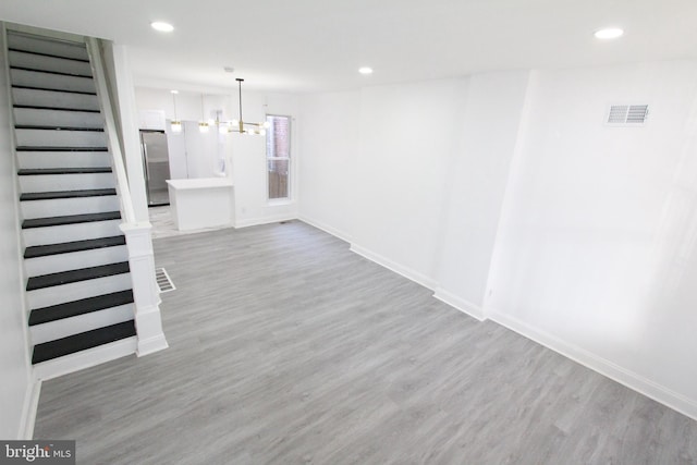 interior space featuring stainless steel fridge, light wood-type flooring, and an inviting chandelier