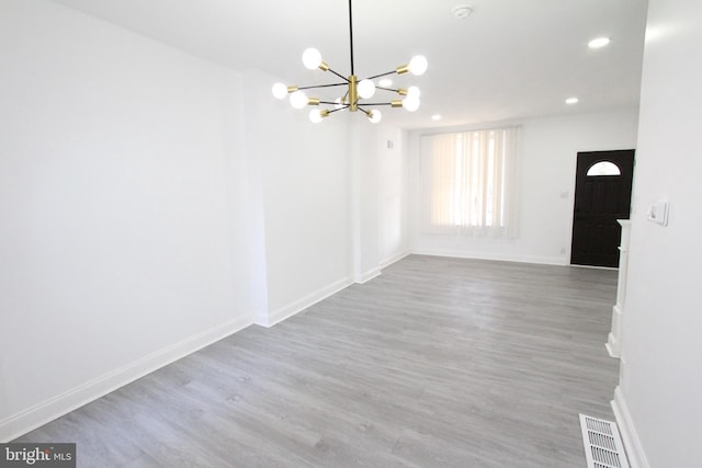 unfurnished room with hardwood / wood-style flooring and a chandelier