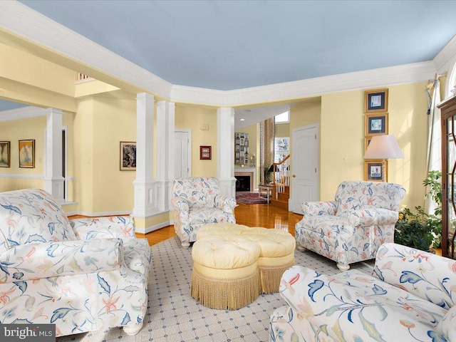 living room with crown molding, hardwood / wood-style flooring, and ornate columns