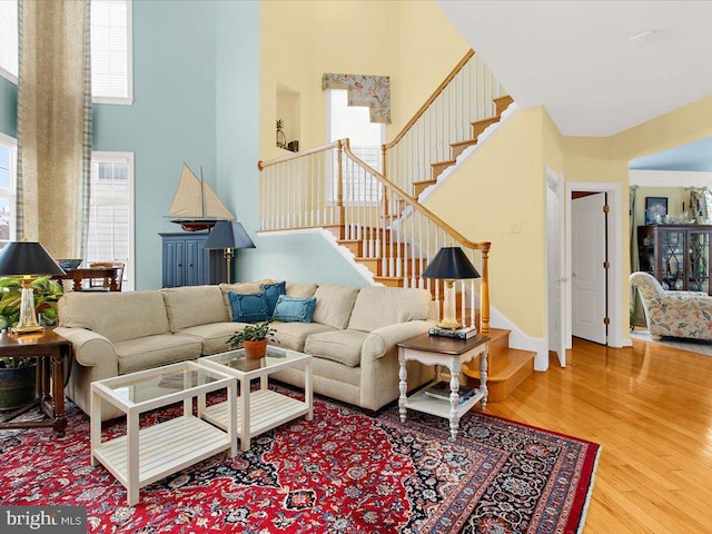 living room with a towering ceiling and hardwood / wood-style flooring