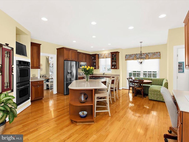 kitchen with a kitchen breakfast bar, a center island, light wood-type flooring, and appliances with stainless steel finishes