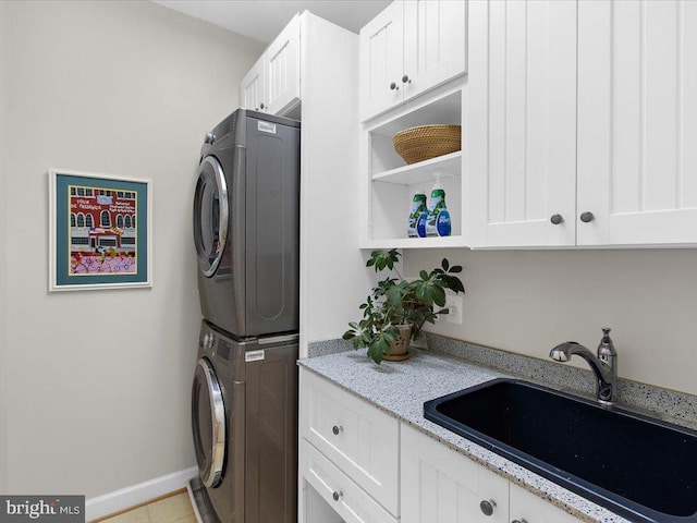 laundry room featuring sink, stacked washer / drying machine, and cabinets