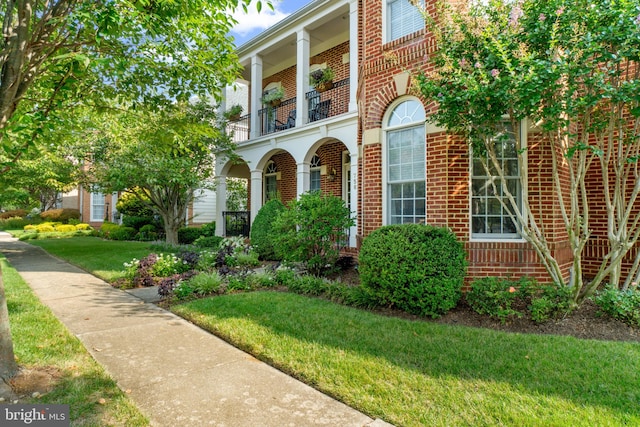 view of exterior entry with a lawn and a balcony