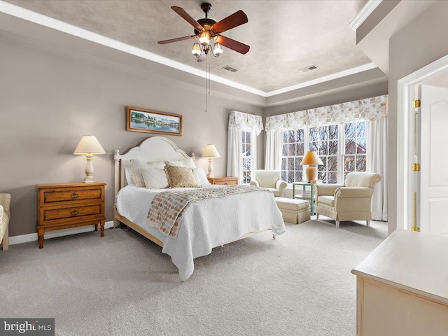 carpeted bedroom with ceiling fan, ornamental molding, and a tray ceiling