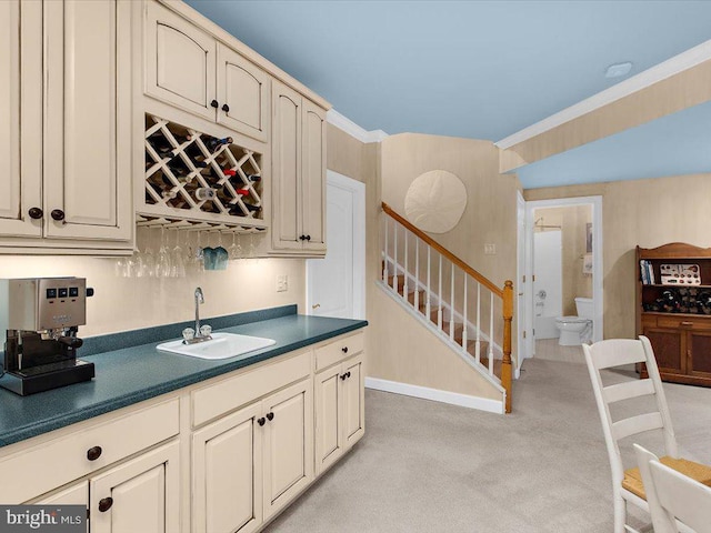 bar with light colored carpet, cream cabinetry, crown molding, and sink