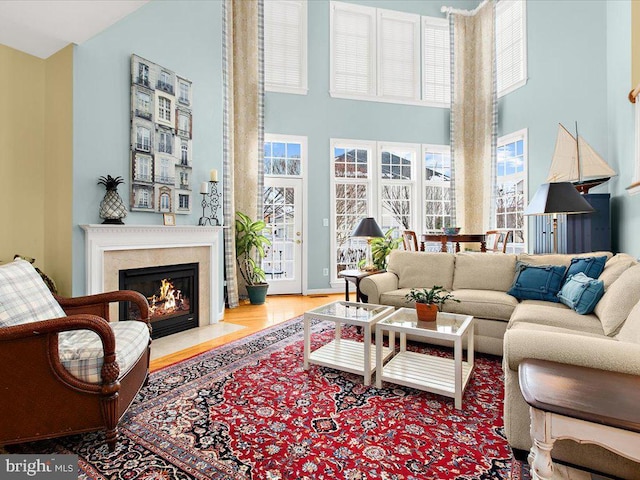 living room with a high ceiling, hardwood / wood-style floors, and a high end fireplace