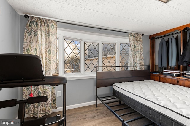 bedroom featuring a drop ceiling, a closet, and wood-type flooring