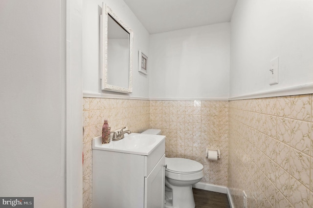 bathroom with tile walls, toilet, and vanity