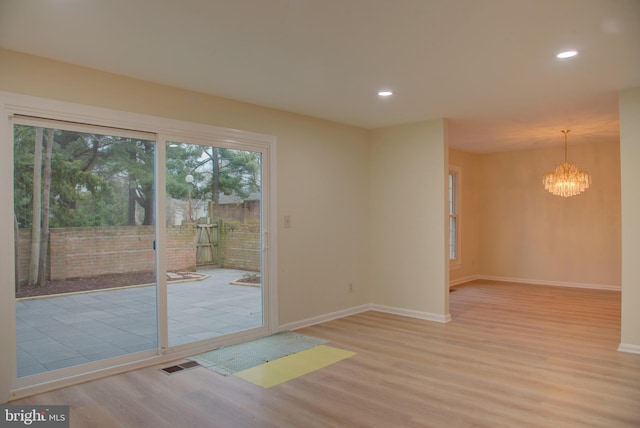 unfurnished room with a notable chandelier and light hardwood / wood-style flooring