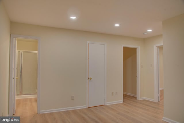 unfurnished bedroom featuring ensuite bathroom, a walk in closet, and light wood-type flooring