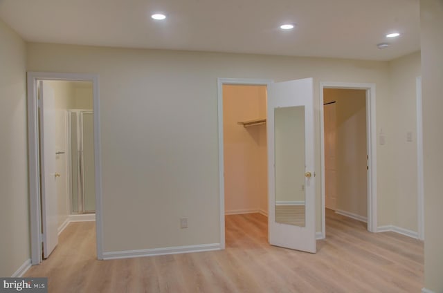 unfurnished bedroom featuring light hardwood / wood-style flooring, a spacious closet, and a closet