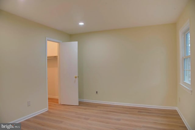 unfurnished bedroom featuring light wood-type flooring, a spacious closet, and a closet