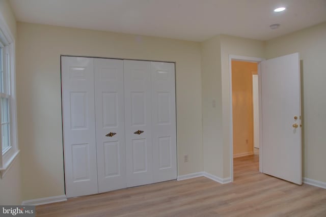 unfurnished bedroom with light wood-type flooring and a closet