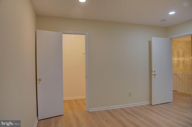 unfurnished bedroom featuring light hardwood / wood-style floors, a walk in closet, and a closet