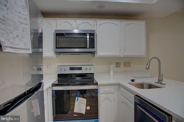 kitchen with appliances with stainless steel finishes, white cabinetry, and sink