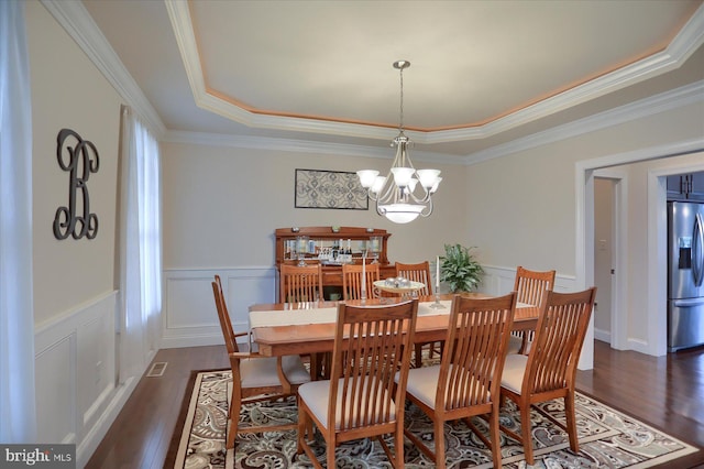 dining room featuring a tray ceiling, crown molding, dark wood-type flooring, and an inviting chandelier