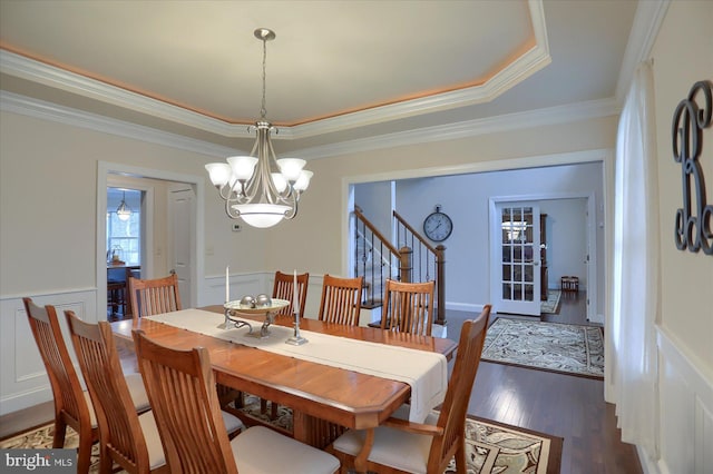 dining space featuring a tray ceiling, crown molding, dark hardwood / wood-style flooring, and a notable chandelier