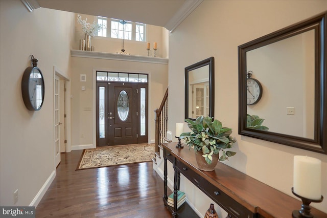 entryway featuring a towering ceiling, dark wood-type flooring, and ornamental molding