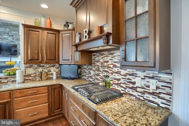 kitchen featuring decorative backsplash, light stone counters, stainless steel gas cooktop, and dark wood-type flooring