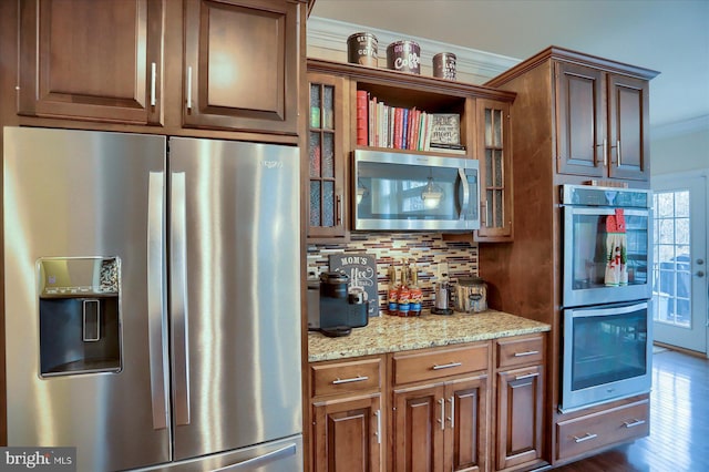 kitchen with decorative backsplash, appliances with stainless steel finishes, light stone counters, and crown molding