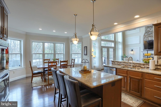 kitchen featuring a kitchen bar, light stone countertops, sink, decorative light fixtures, and a center island