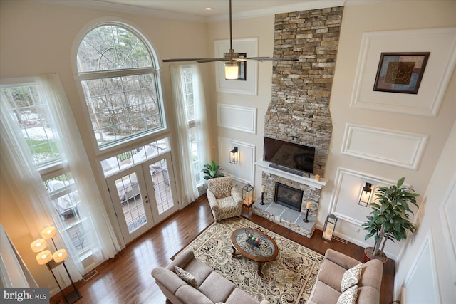 living room featuring ceiling fan, a fireplace, a towering ceiling, and hardwood / wood-style flooring