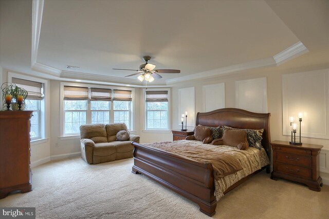 carpeted bedroom featuring a raised ceiling, ceiling fan, and crown molding