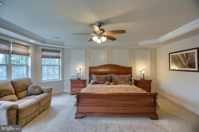 bedroom featuring light carpet, a tray ceiling, and ceiling fan