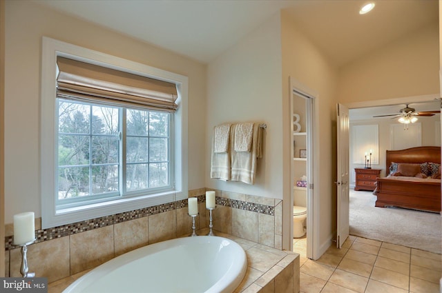 bathroom featuring lofted ceiling, tile patterned floors, ceiling fan, toilet, and tiled tub