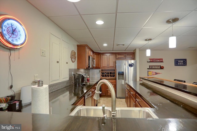 kitchen with a drop ceiling, decorative light fixtures, sink, and appliances with stainless steel finishes