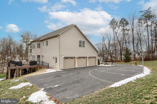 view of property exterior featuring a garage, basketball court, and a wooden deck