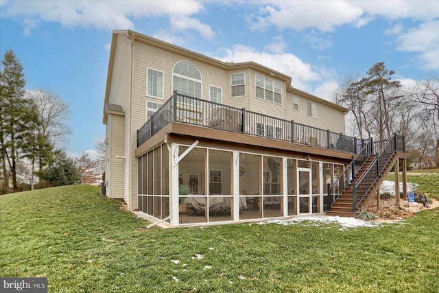 rear view of property with a sunroom, a deck, and a lawn