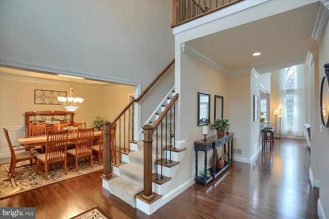 staircase featuring wood-type flooring, a high ceiling, and an inviting chandelier