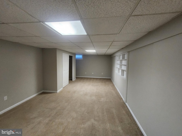 basement with a drop ceiling, built in features, and carpet floors