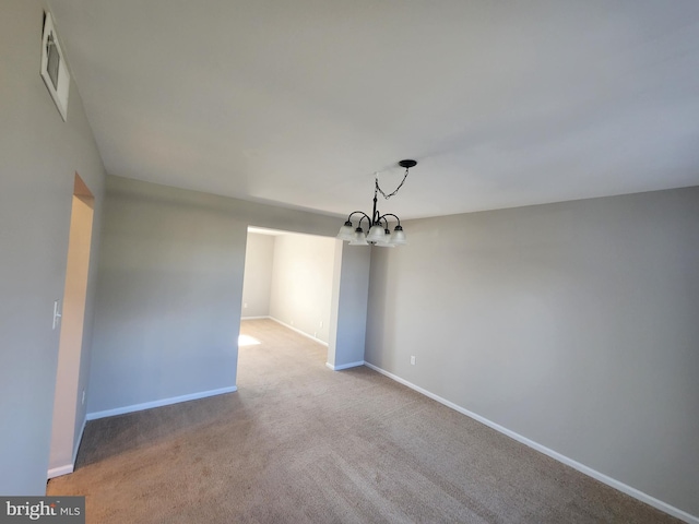 carpeted empty room featuring a chandelier