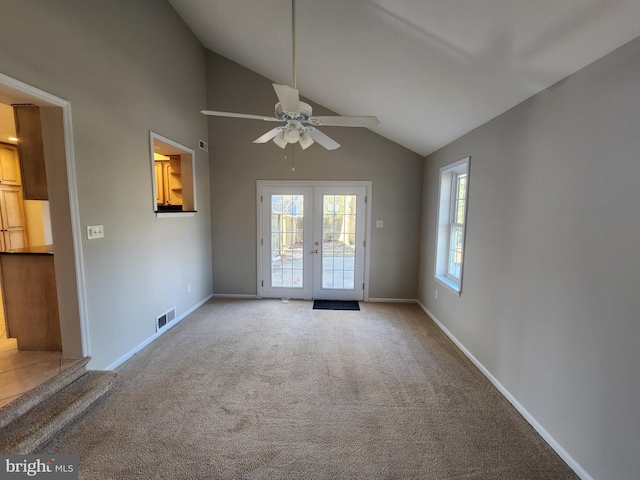 unfurnished living room featuring ceiling fan, vaulted ceiling, light colored carpet, and french doors