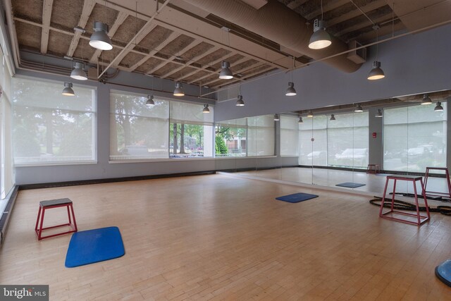 workout room with a high ceiling, hardwood / wood-style floors, and ceiling fan