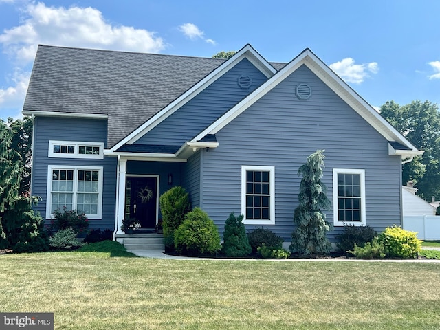 view of front of property featuring roof with shingles and a front lawn