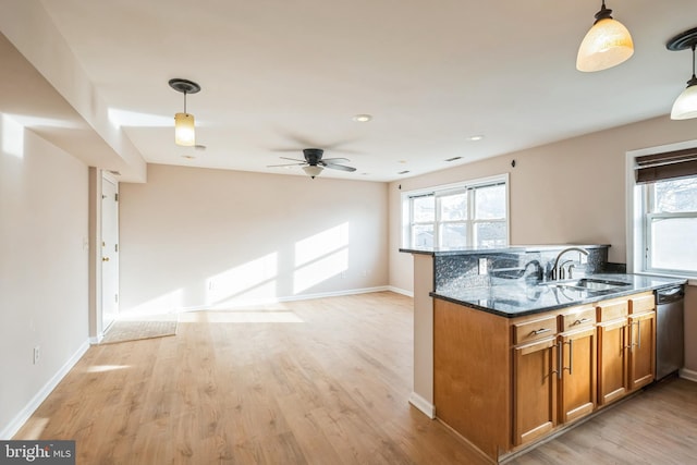 kitchen featuring dark stone countertops, light wood-type flooring, and hanging light fixtures