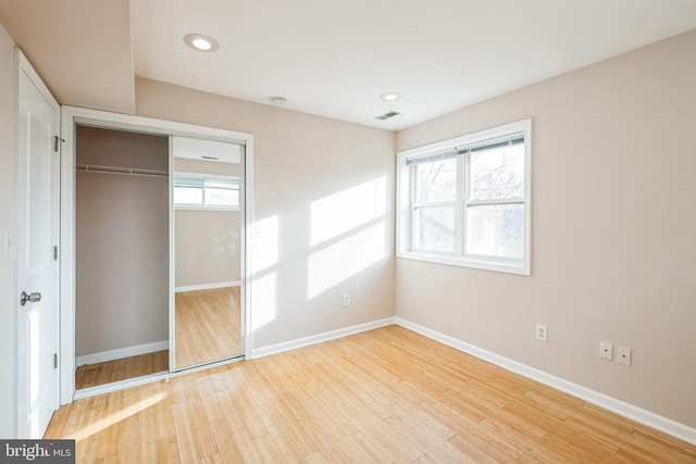 unfurnished bedroom with light wood-type flooring and a closet