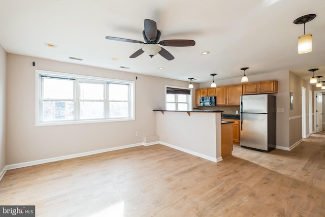 kitchen with kitchen peninsula, decorative backsplash, ceiling fan, pendant lighting, and stainless steel refrigerator