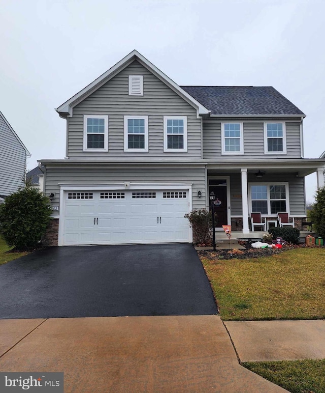 view of front of property featuring covered porch, a front yard, and a garage