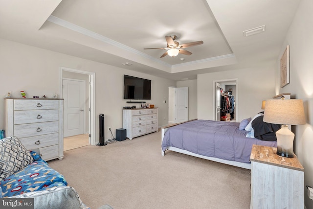 bedroom featuring crown molding, a spacious closet, light carpet, a raised ceiling, and a closet