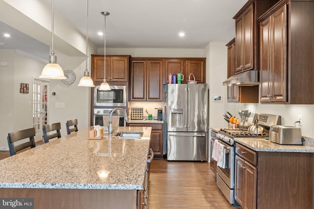 kitchen featuring appliances with stainless steel finishes, pendant lighting, a center island with sink, and sink