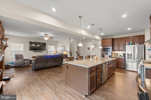 kitchen featuring sink, hanging light fixtures, an island with sink, hardwood / wood-style flooring, and stainless steel appliances