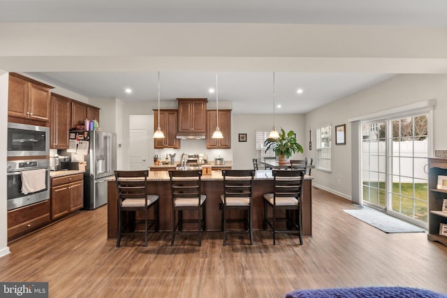 kitchen with a kitchen island with sink, decorative light fixtures, a kitchen breakfast bar, and appliances with stainless steel finishes