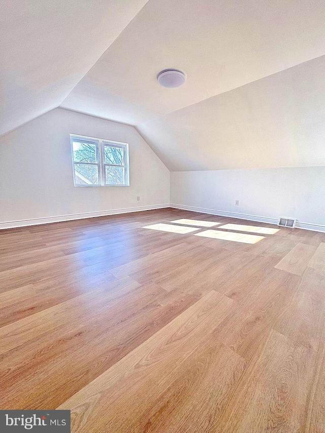 additional living space with light hardwood / wood-style flooring and vaulted ceiling